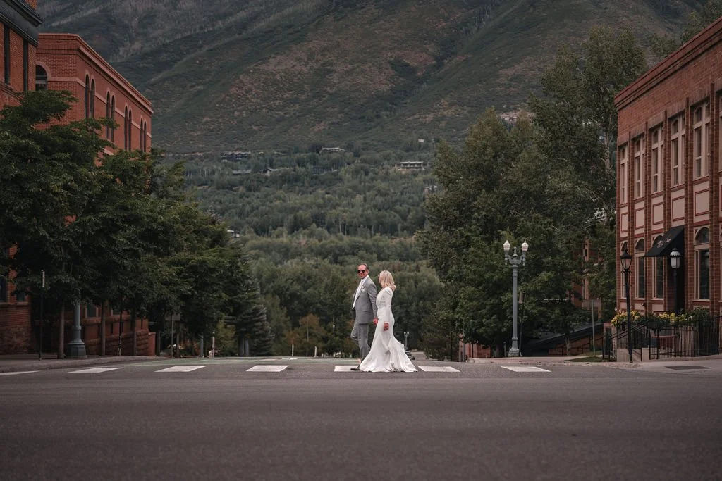 Newlyweds standing in an empty street with mountains behind them