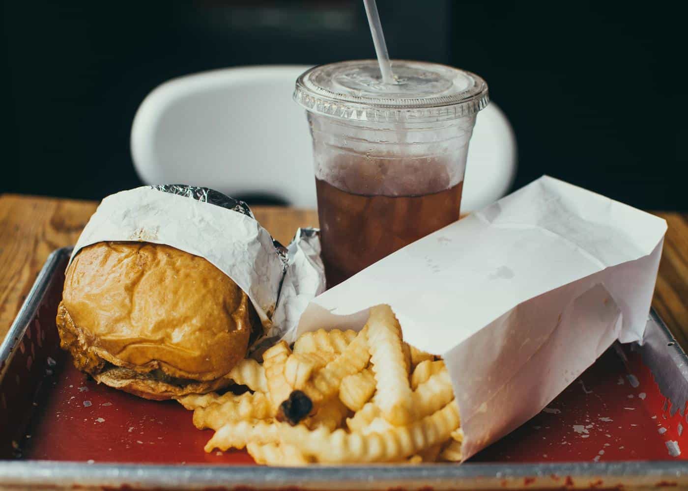 Image of a fast food burger, fries, and a drink on a tray