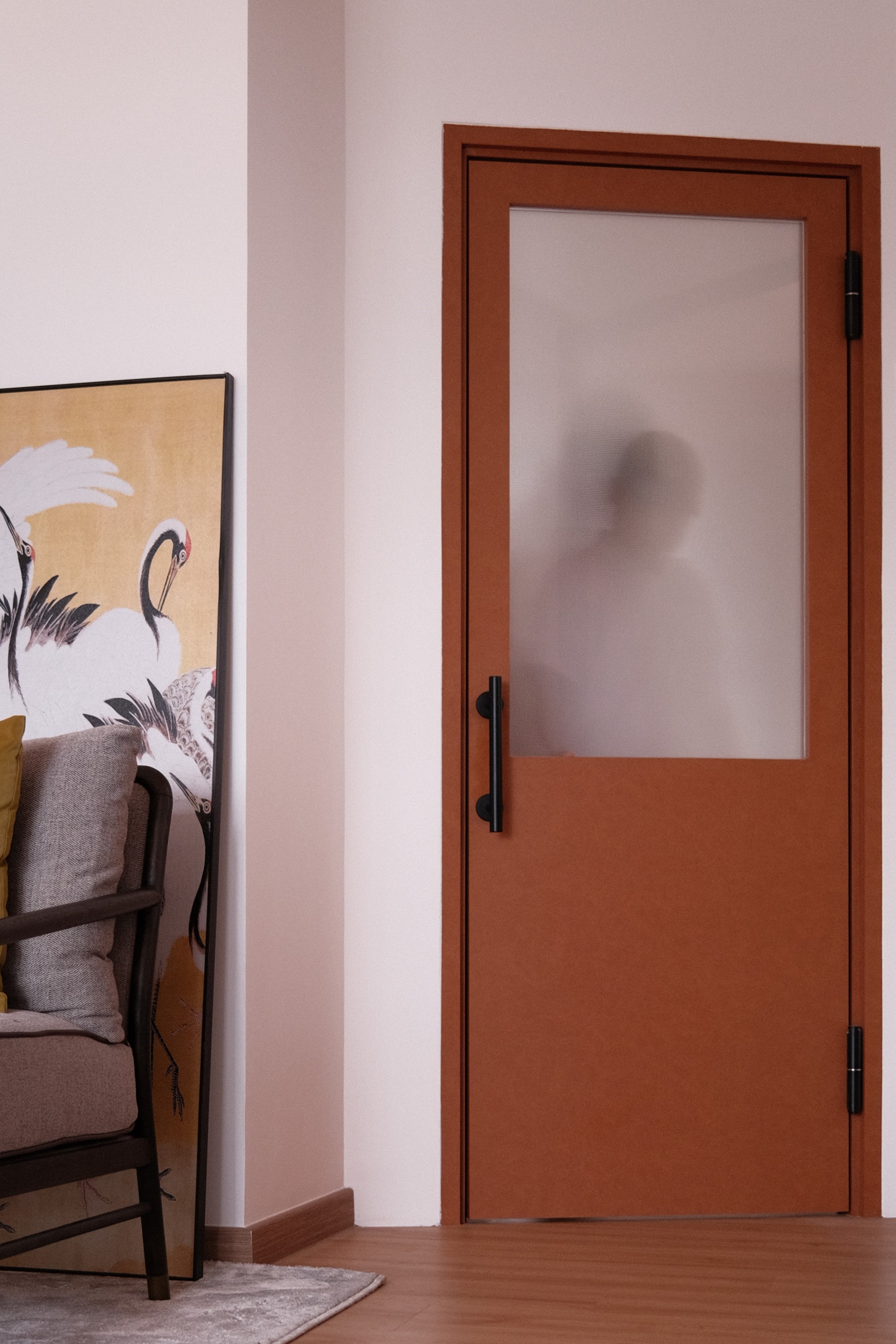 Minimalist flush-panel terracotta door beside a rich wood veneer wardrobe, creating a seamless modern entryway.