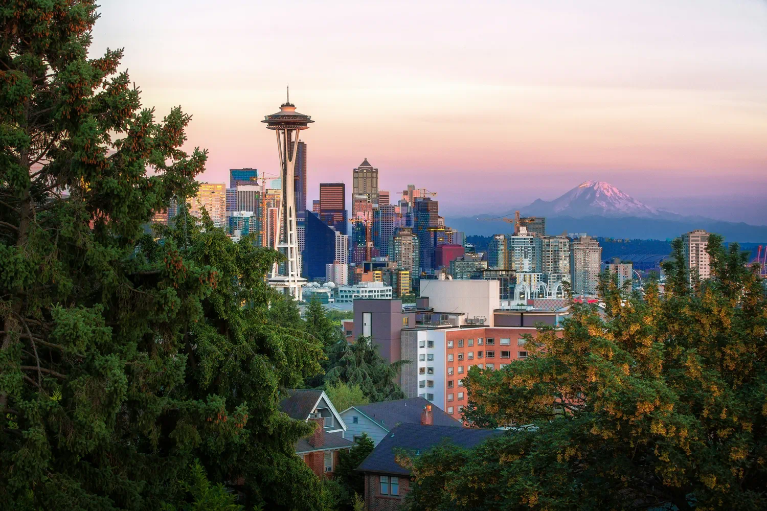 Seattle skyline at sunset with the Space Needle and Mount Rainier in the distance.