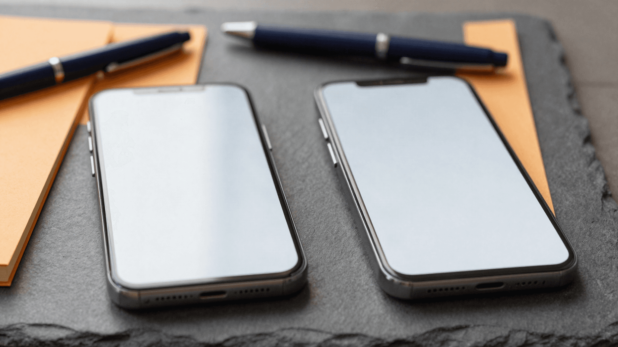 Zwei Smartphones nebeneinander auf Schieferplatte (KI-generiert)