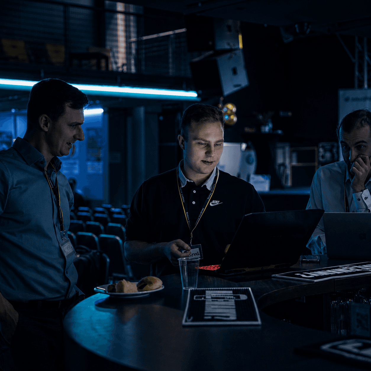 person discussing while standing in front of a large screen in front of people inside dim-lighted room