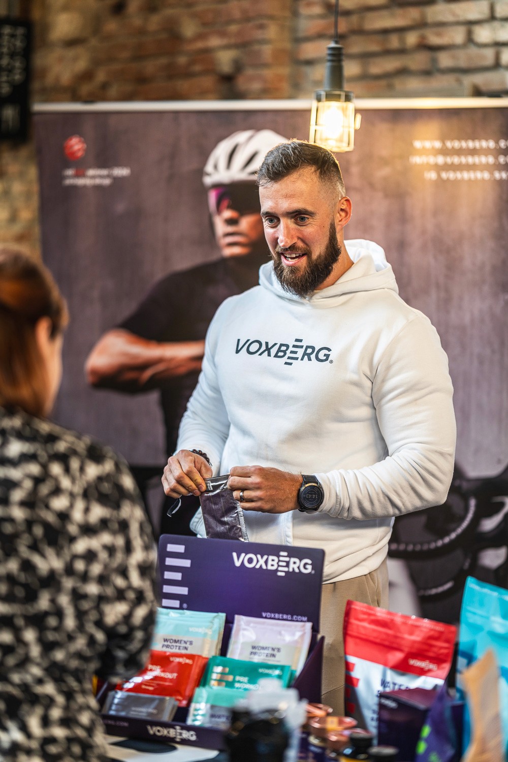 Brand ambassador engaging with visitors at a sponsor booth during a corporate event.