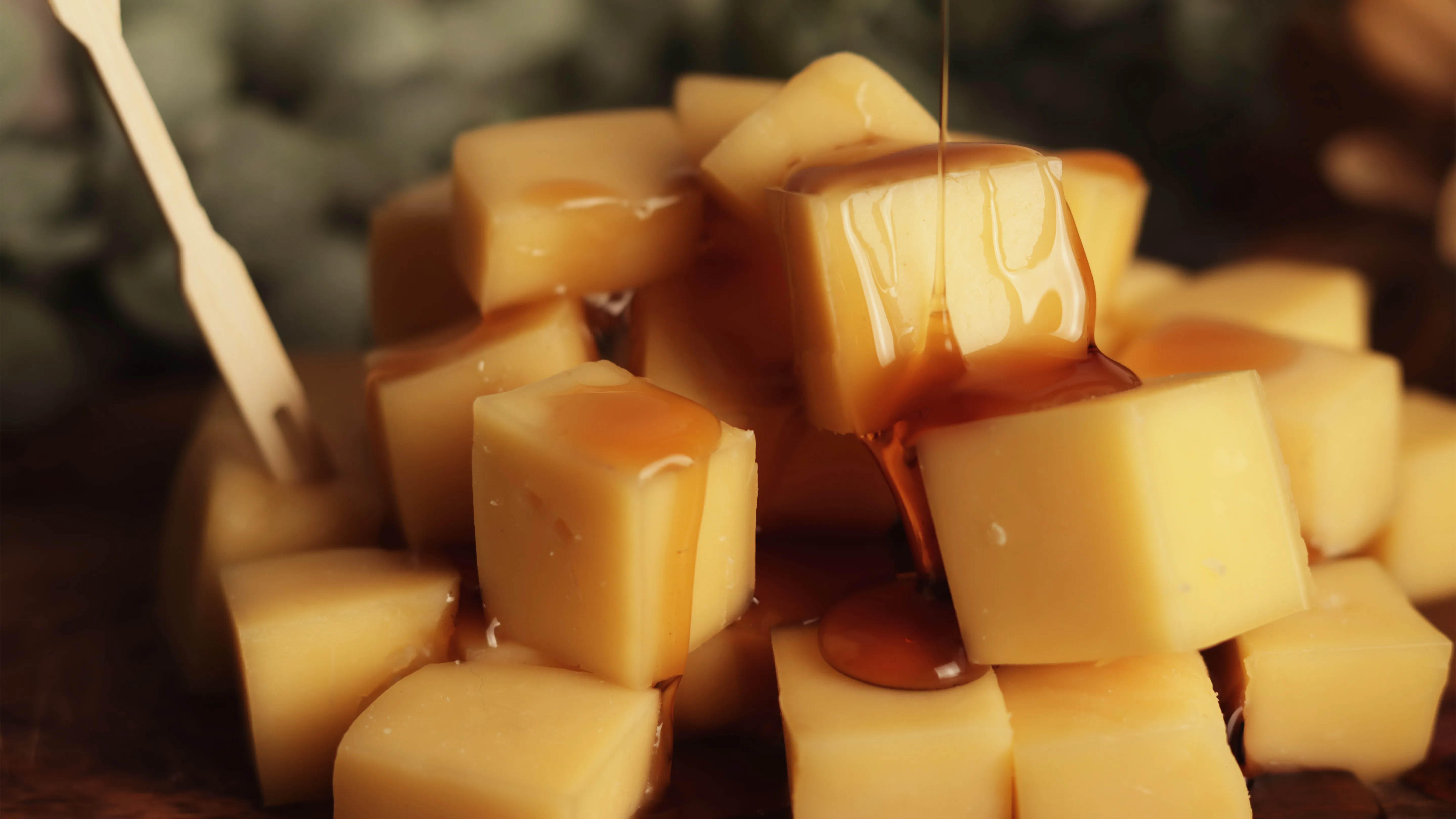 Cubos de queso con miel sobre tabla de madera