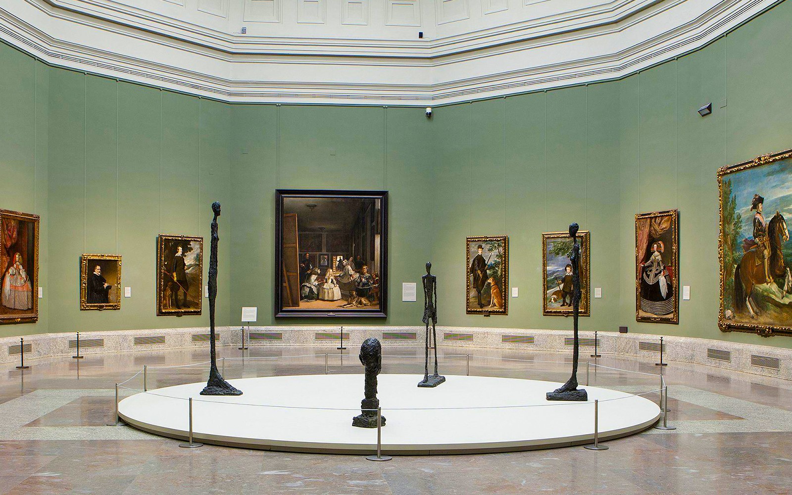 Visitors exploring art exhibits inside the Prado Museum, Madrid, during a guided tour.