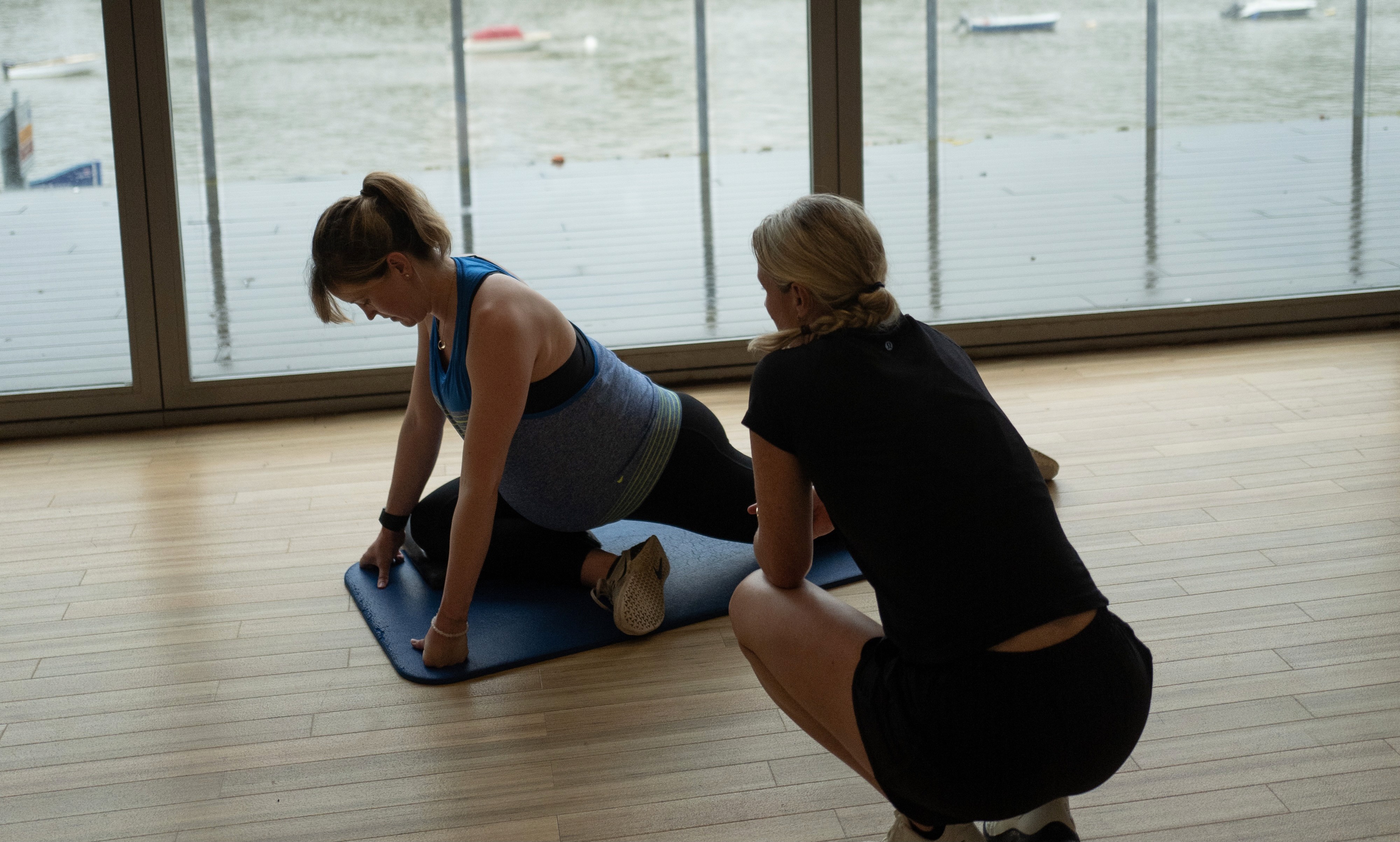 Personal trainer helping antenatal client with workout