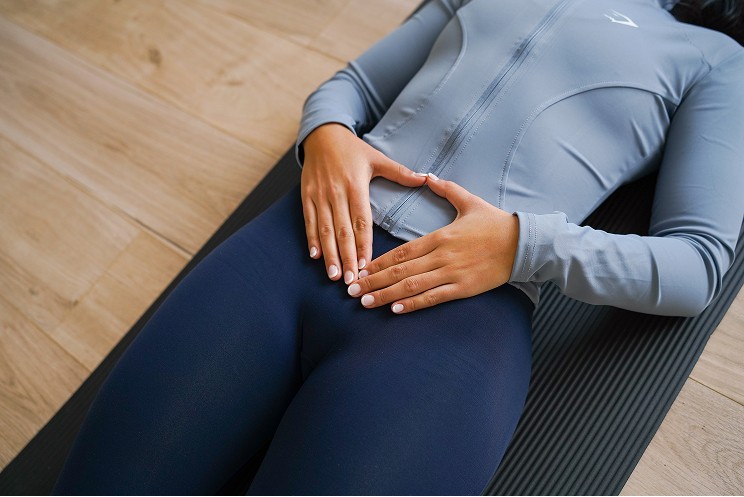 A young woman with wet hair, leaning back in a bath with her eyes closed. The sunlight reflects off the water, creating a serene and tranquil atmosphere.
