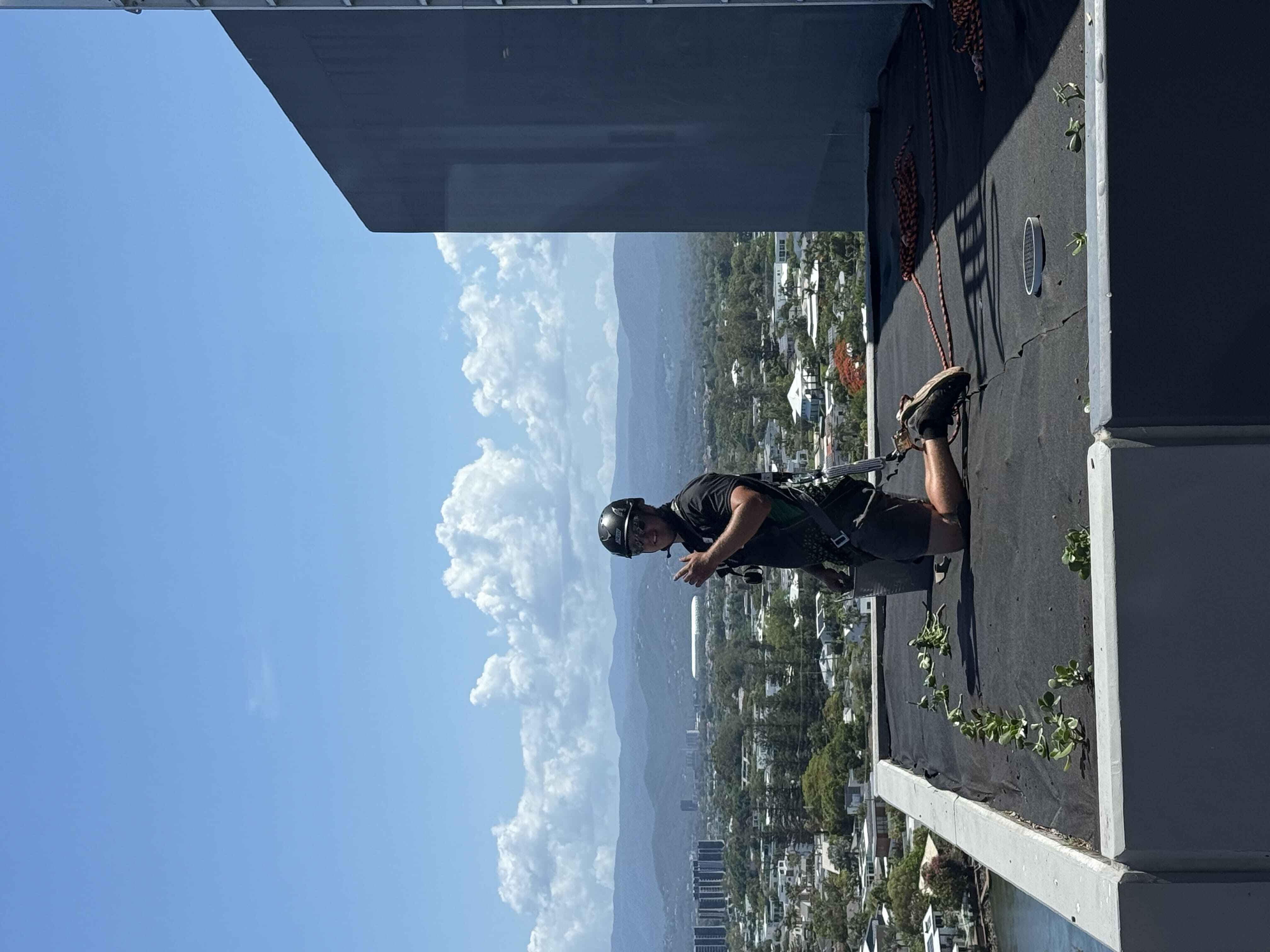 Hepburn Property Maintenance team member in safety harness completing high access rooftop garden maintenance Surfers Paradise Gold Coast