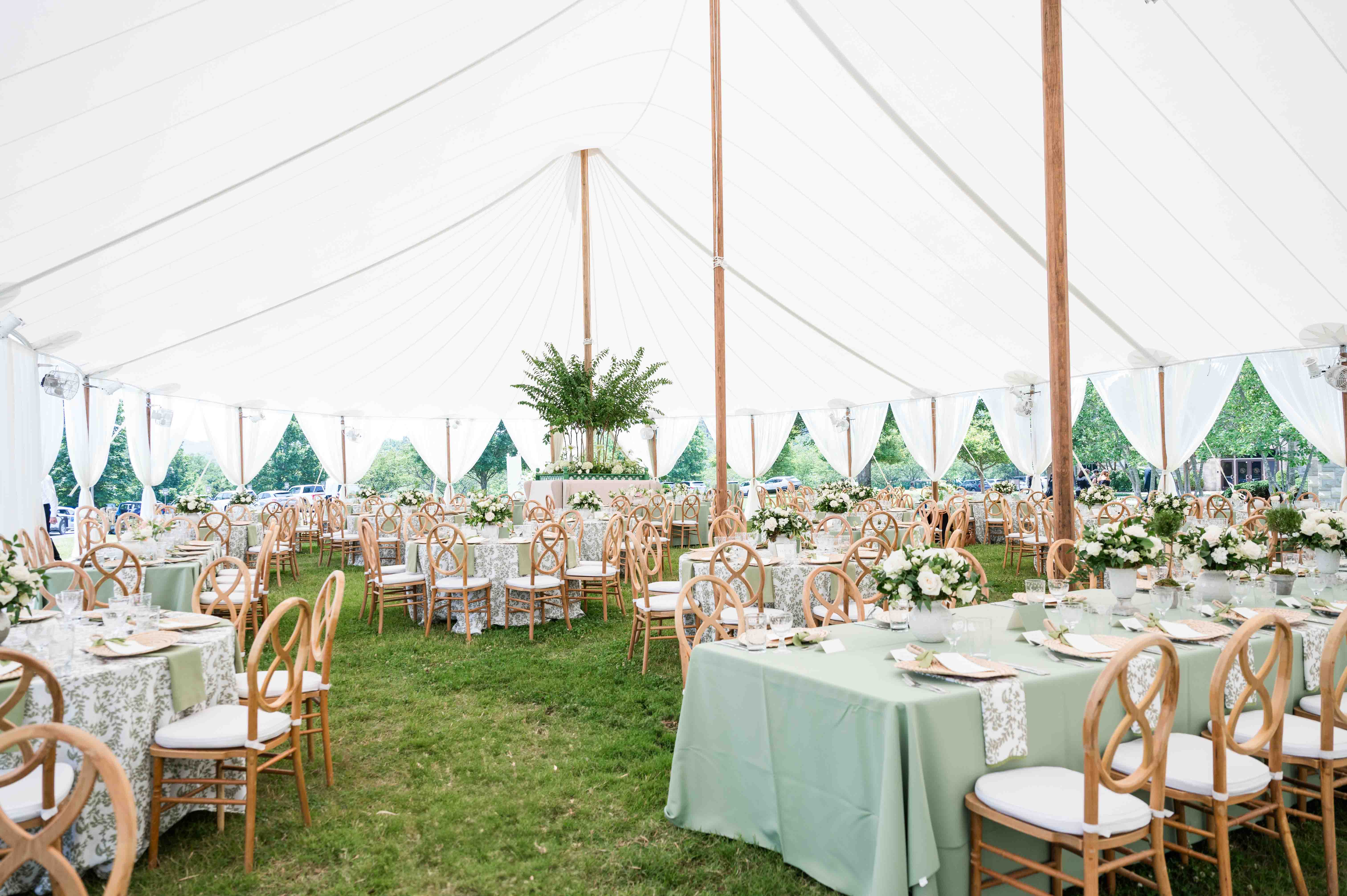 Image of wedding reception underneath a sail tent outside on a summer day.