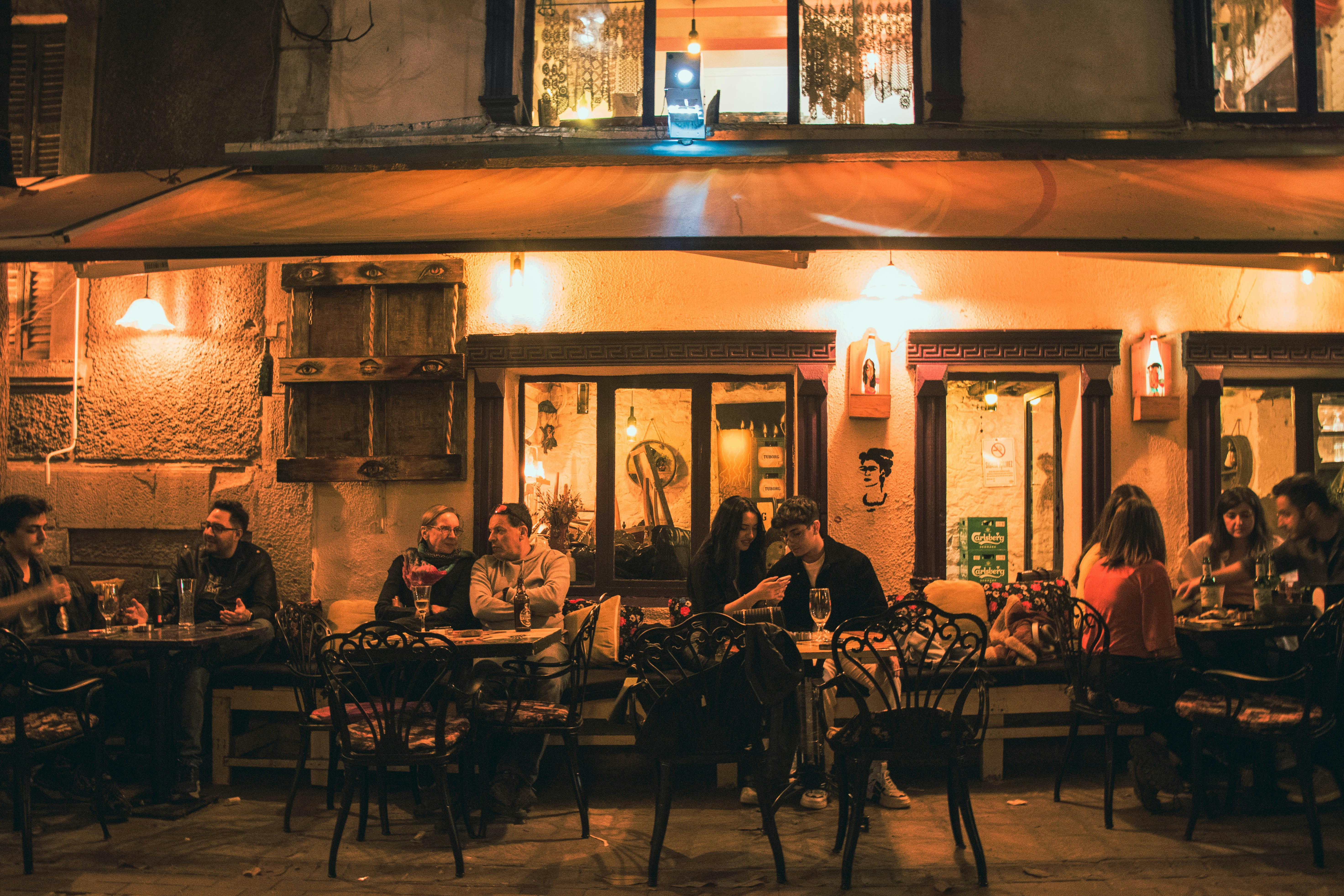 A group of people sitting outside of a restaurant at night