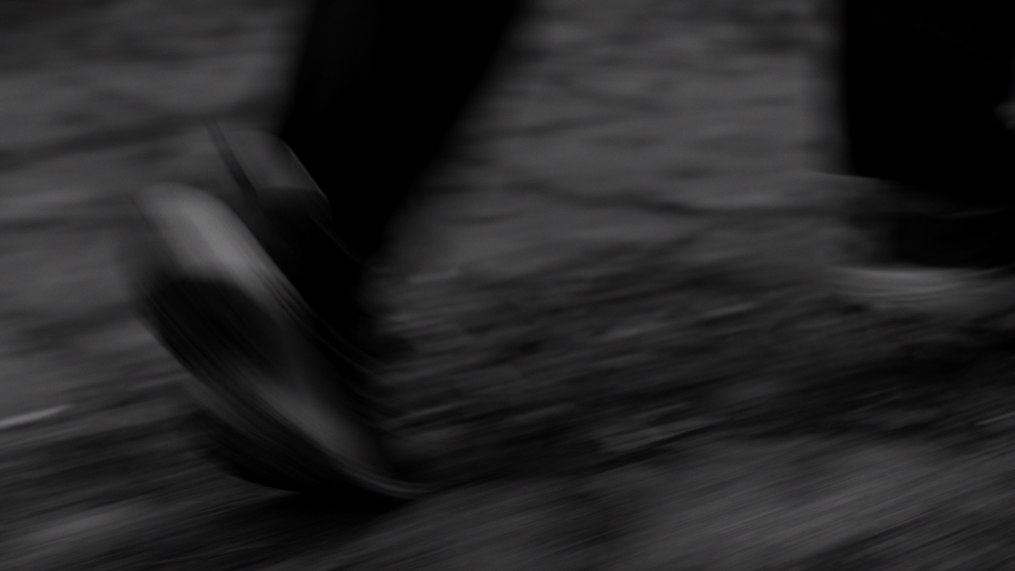 Low angle shot of feet running on wet pavement, motion blur effect.