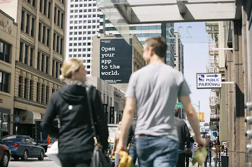 a man walking down a street past a large poster