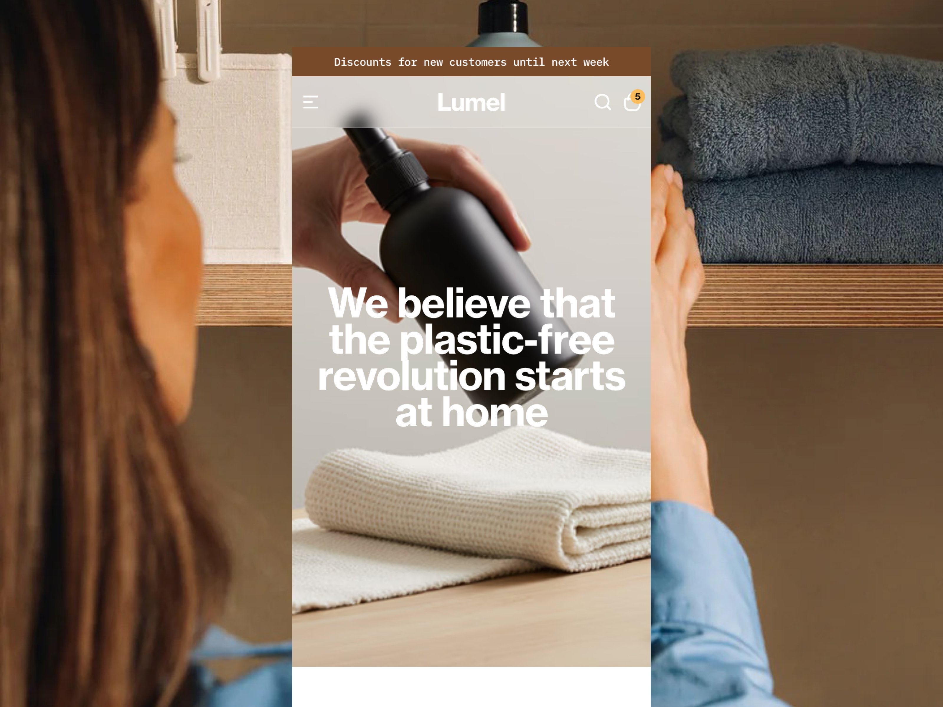 Lumel website template hero section showing a woman holding a dark reusable spray bottle next to folded towels with the headline "We believe that the plastic-free revolution starts at home