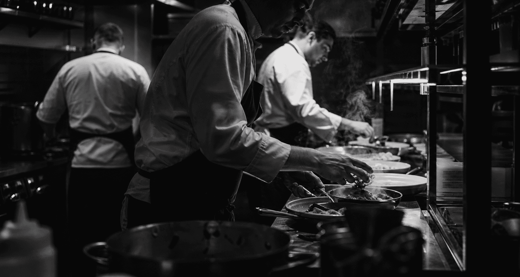 Professional chefs working through a busy kitchen service in rising steam