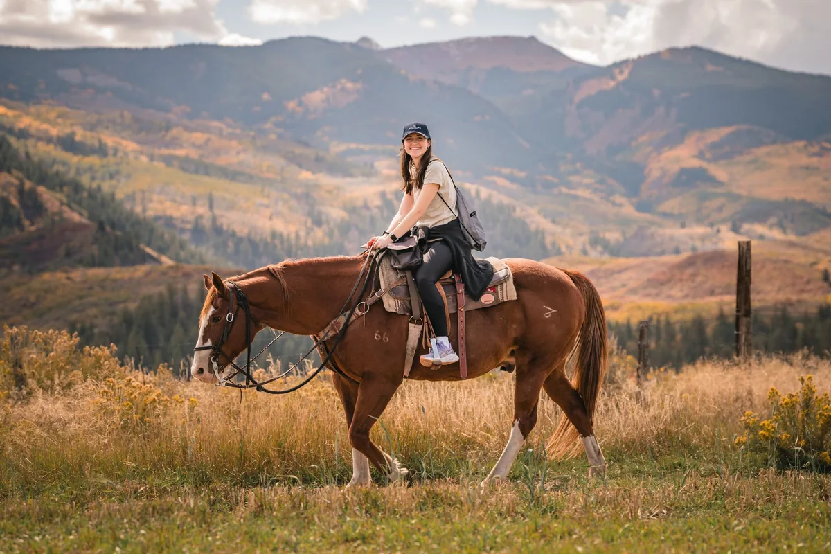 Retreat group riding horseback through fall aspens near Snowmass