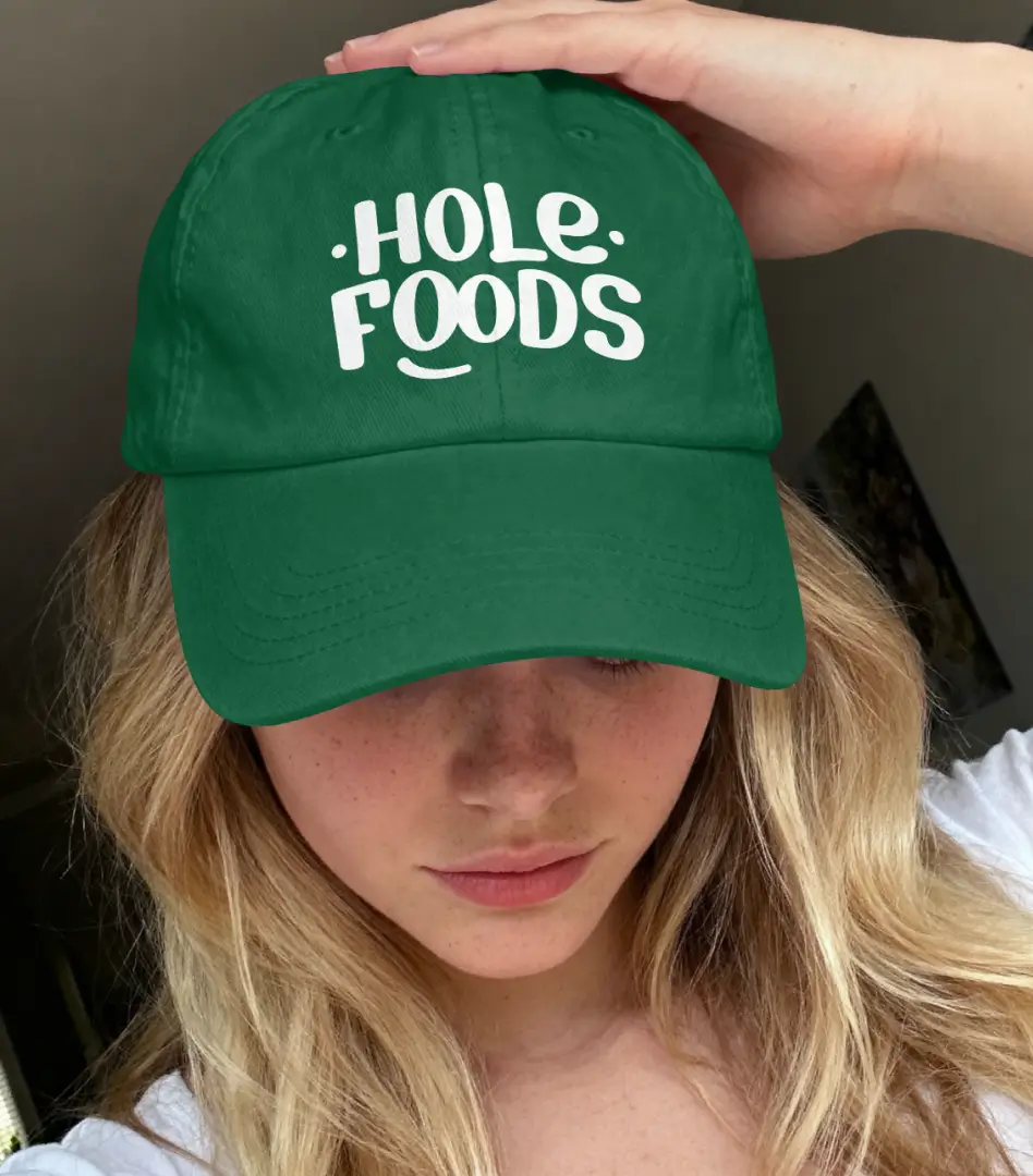 Green Hole Foods branded apron with an all-over line-art pattern of donuts, pretzels, and cheese, displayed on a mannequin.
