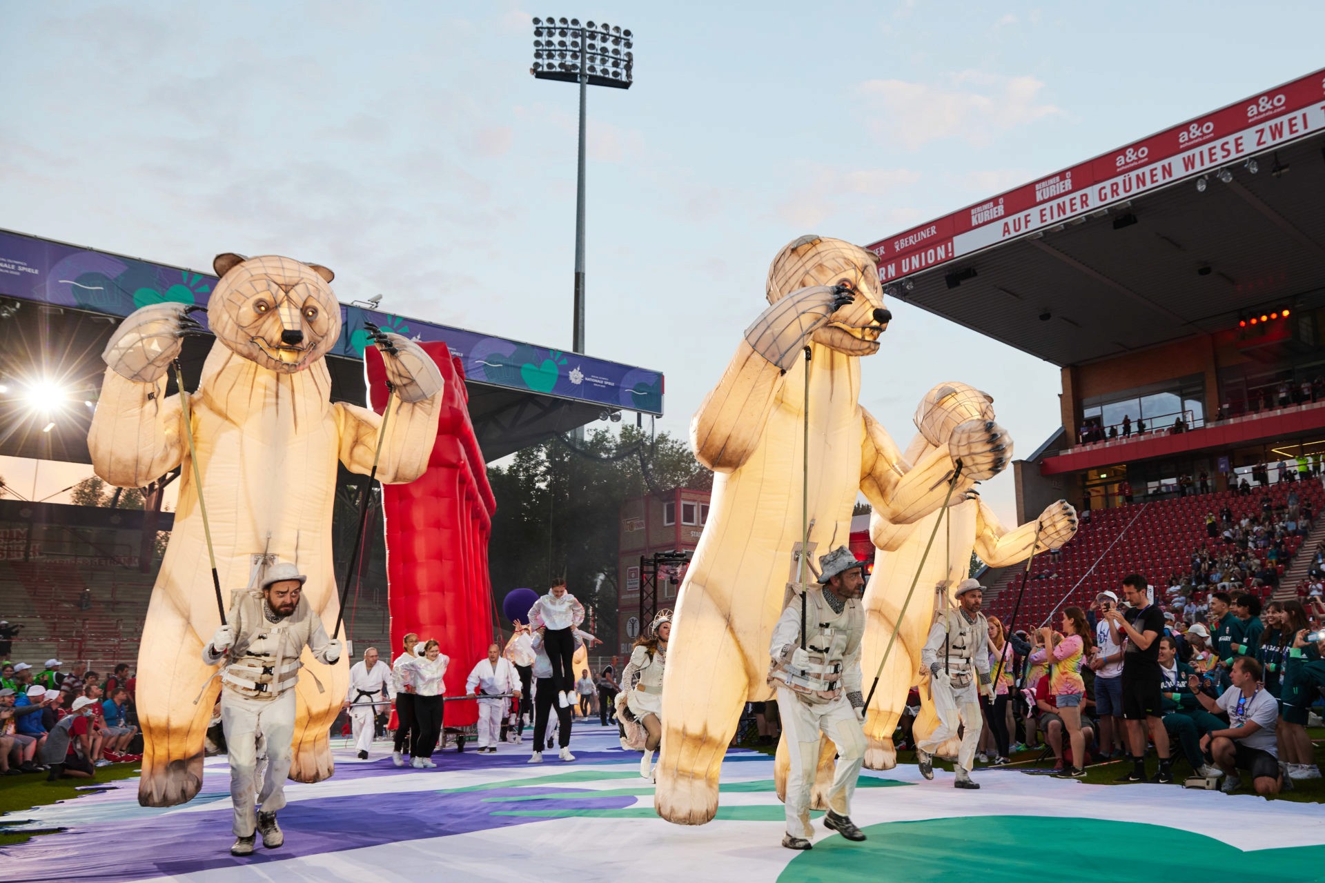 Das Bild zeigt die Bären von Remue Ménage und die Judoka mit dem Brandenburger Tor in der Opening Ceremony der Special Olympics Nationale Spiele 2022 Berlin choreographiert von Nicole Wiese.