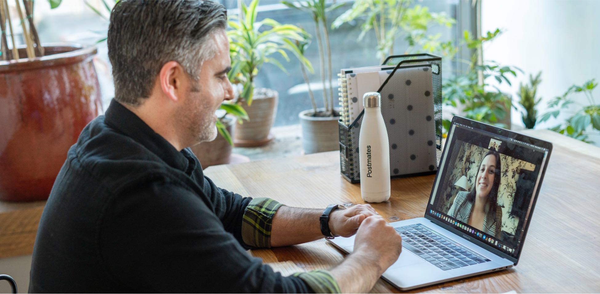 A person working on a laptop with plants and buildings inside.