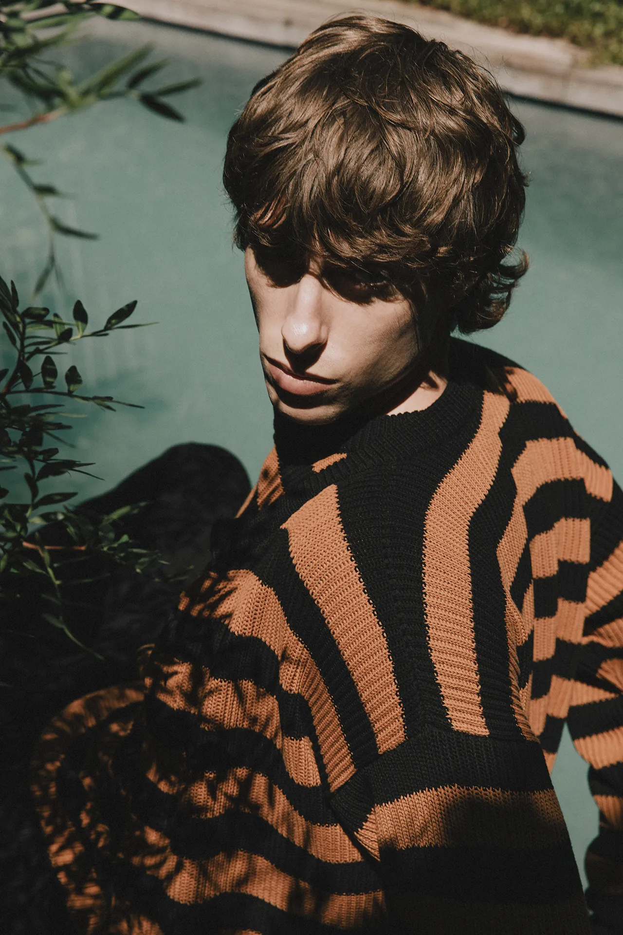 Detail shot of Annapurna SS26 collection black and rust striped ribbed knitwear with a crew neck design.