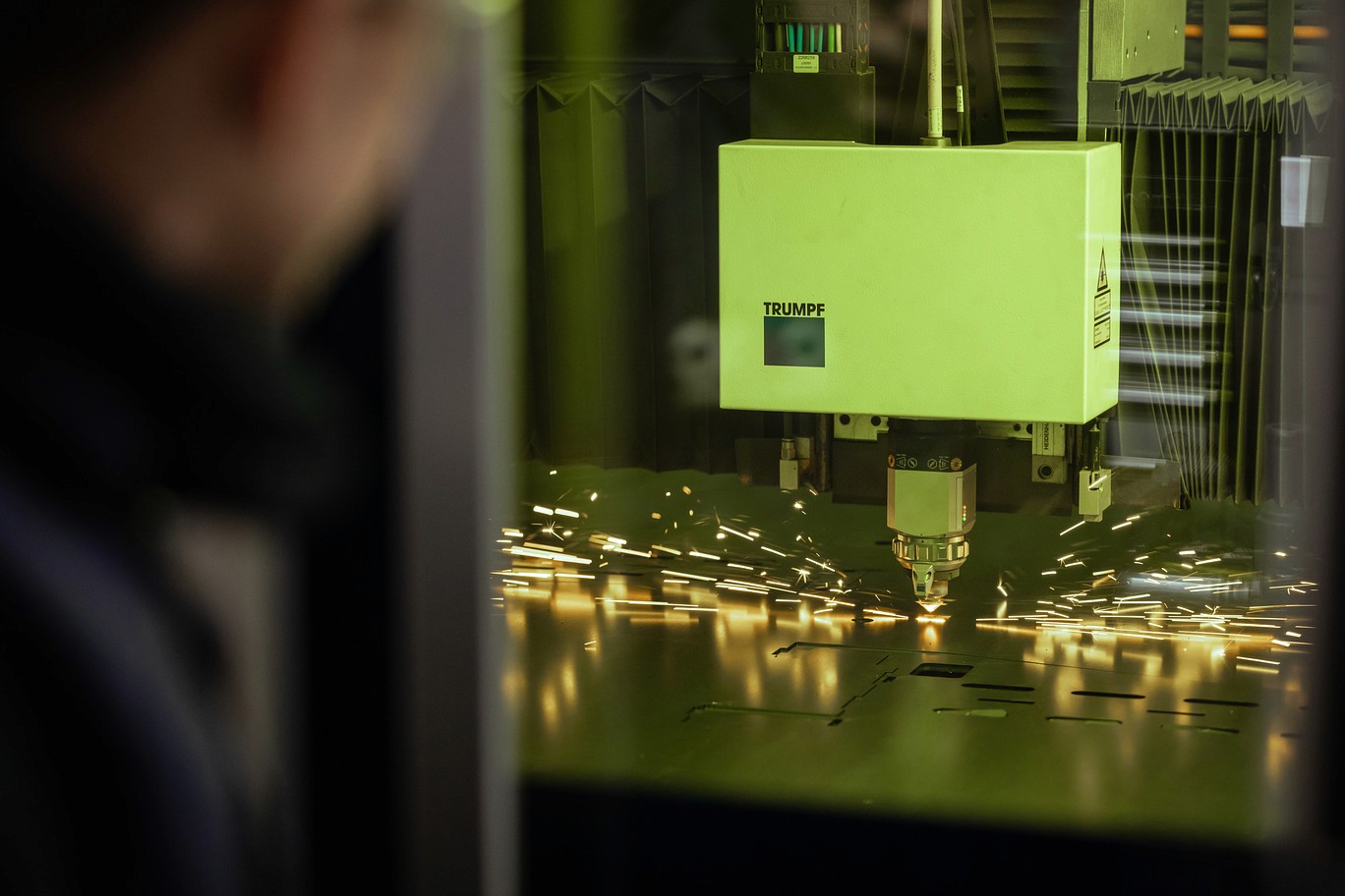 Trumpf laser cutting machine cutting sheet metal with visible sparks inside a workshop.