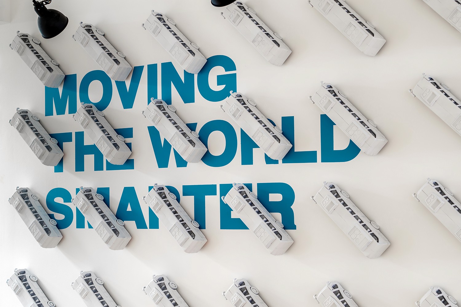 עיצוב משרדים מבוסס מיתוג: דלפק כניסה פיסולי בצורת הלוגו, המשלב צמחייה וניגודיות מול קיר האבן הטבעית