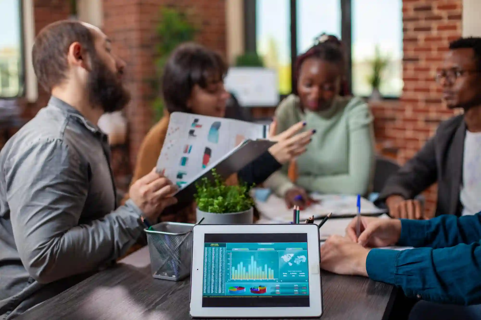 Businesswoman eating a sandwich at her desk during lunch while reviewing growth charts and financial data on her computer.