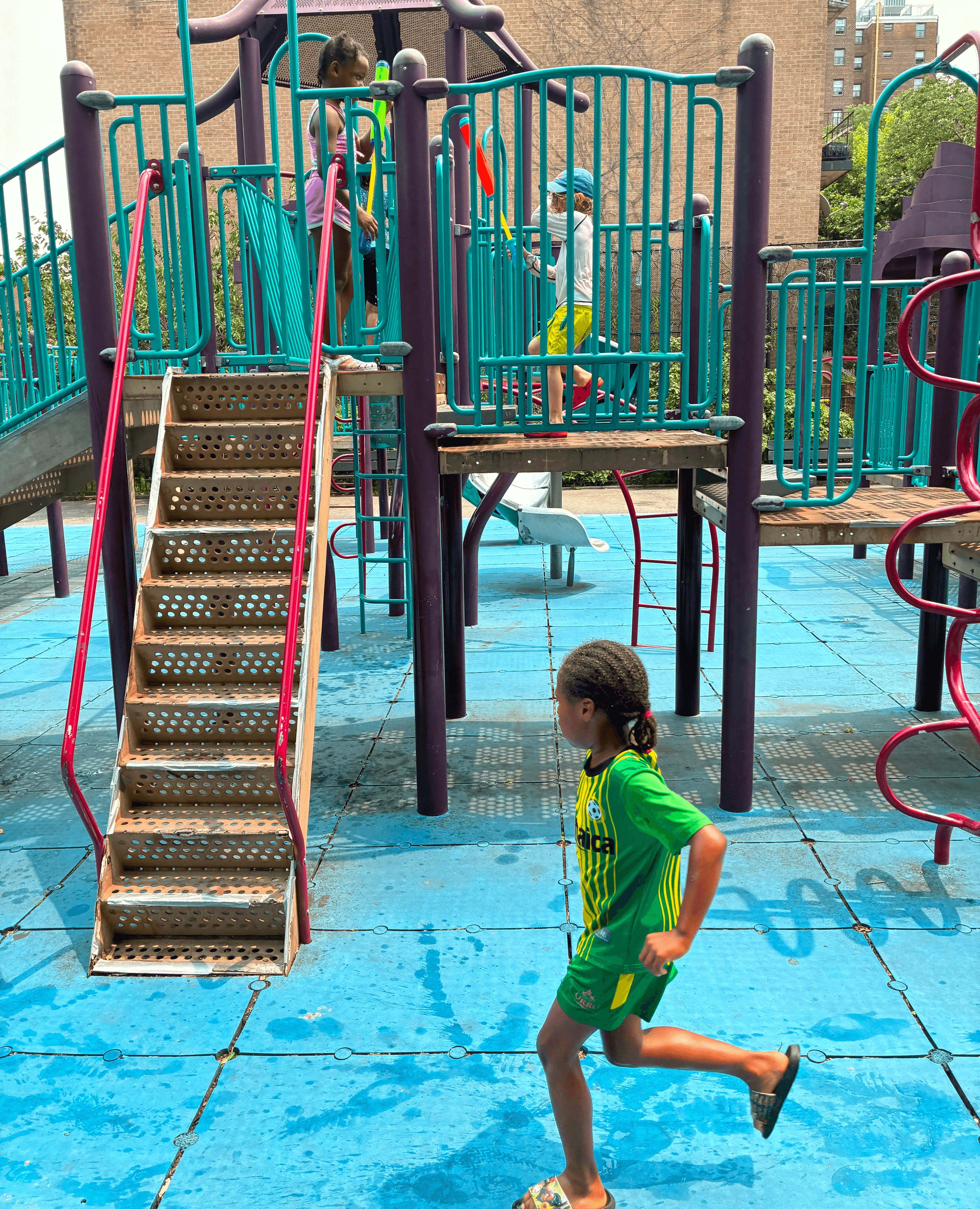 Summer campers frolicking in the sprinklers at a playground.