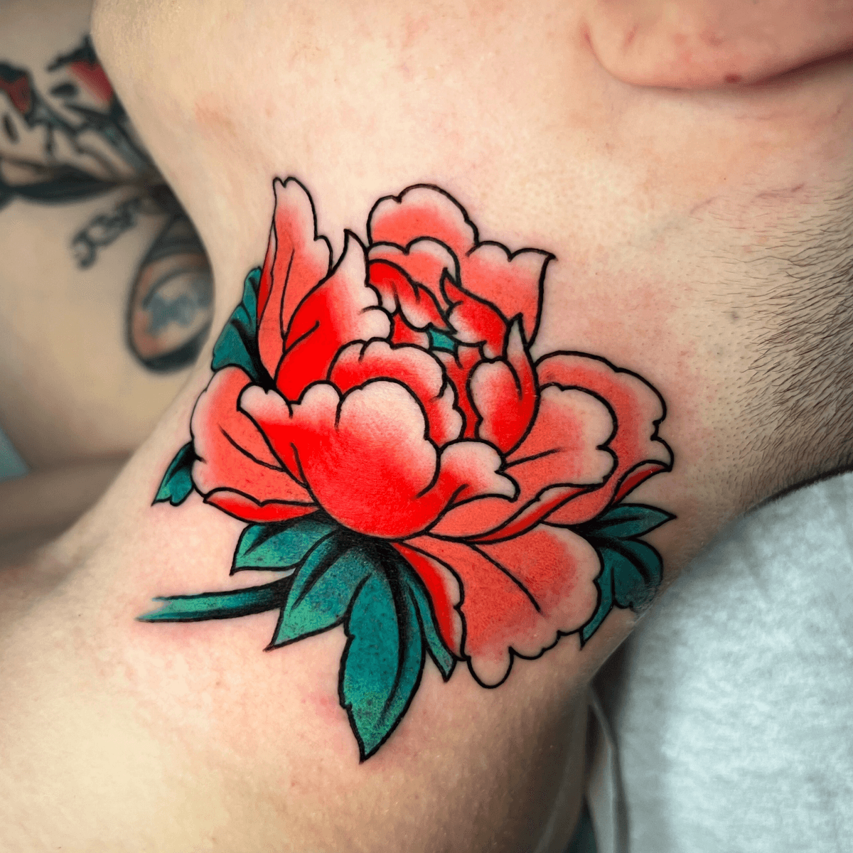 color tattoo of a peony on a neck