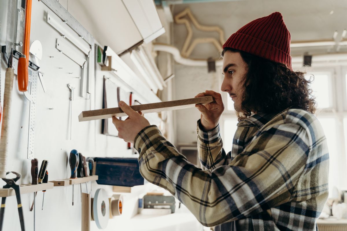 Un artisan vérifie une pièce de bois dans son atelier.