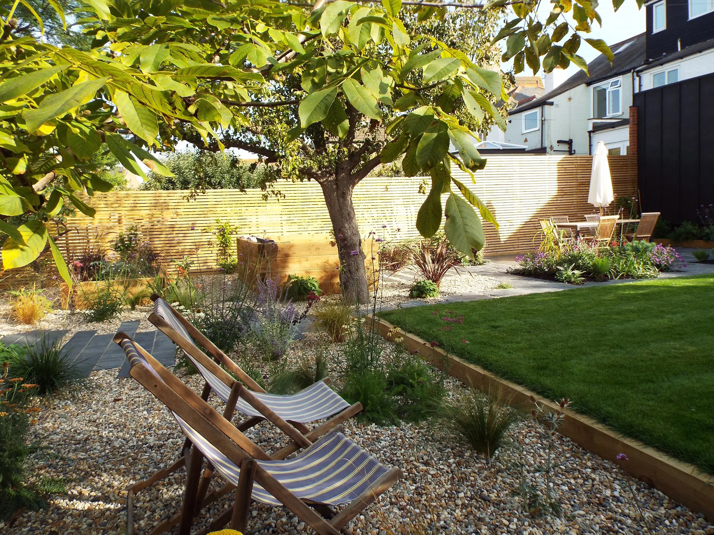 A serene garden scene featuring trees, grass, and gravel pathways, creating a peaceful outdoor space.