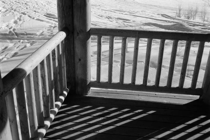 Timber balcony railing casting shadows over the snow field
