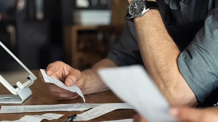 Revision der Kosten des magischen Plans, die eine Person zeigt, die die Projektkosten und Belege überprüft.