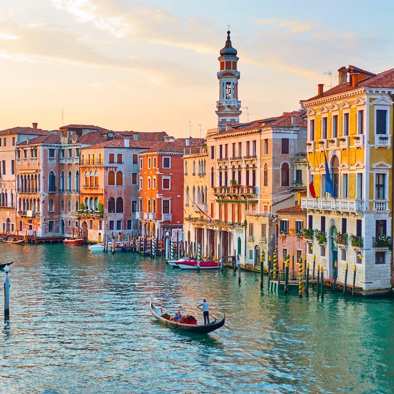 Canal de Veneza com gôndola e edifícios históricos ao pôr do sol