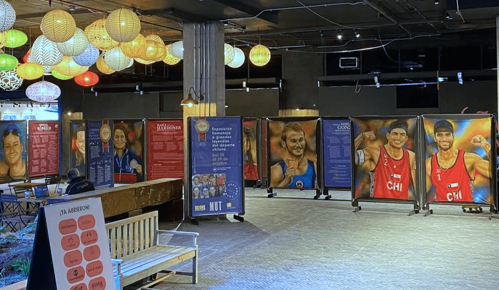 Activación de marca Score Energy Drink. Grupo de personas con latas de Score Energy Drink frente a la pintura de Eliseo Salazar en la exposición Leyendas del Deporte USACH.