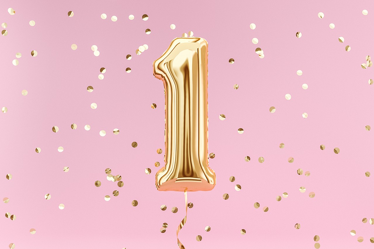 Party balloon in the shape of the number 1 with confetti falling around