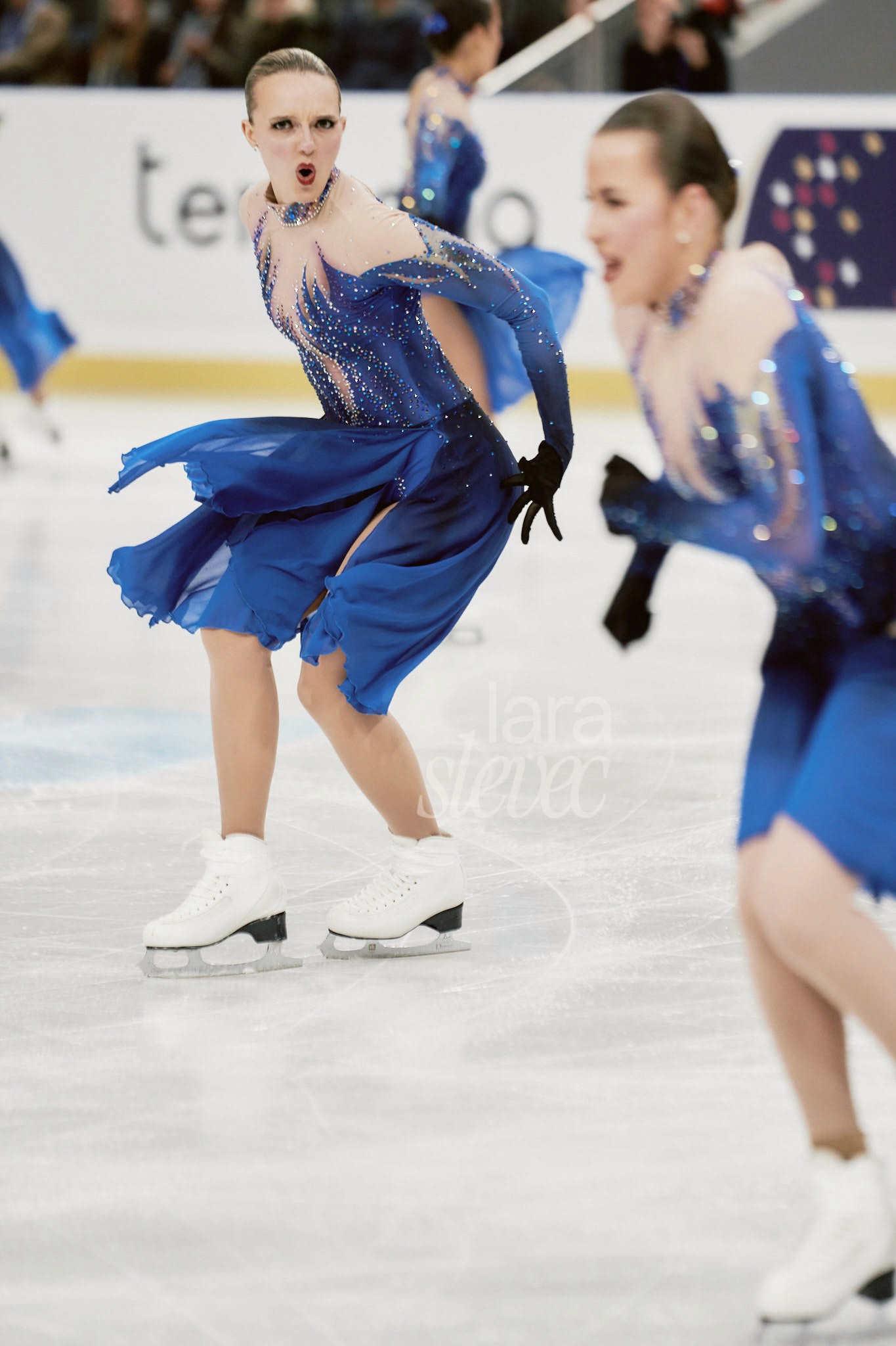 Synchroneiskunstläuferin schaut direkt in die Kamera. Erstaunter, ernster Blick. Team Haydenettes. ISU Synchronized Skating Championships 2026 in Salzburg. Fotografiert von Lara Slevec.