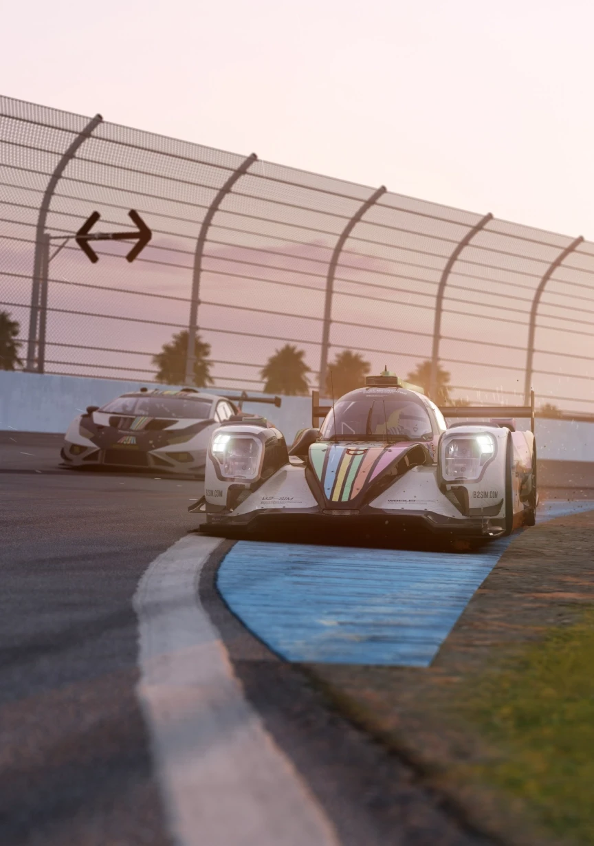 Race car taking a sharp corner at high speed, followed closely by another car, under a pink sunset sky.