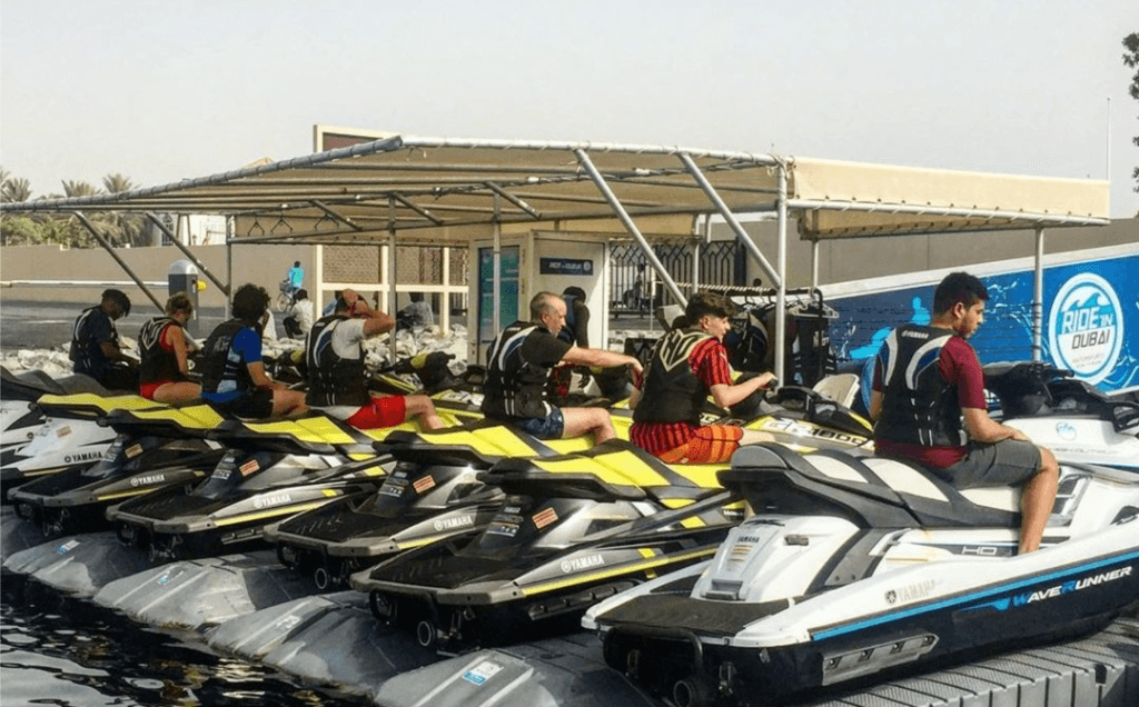 Riders lined up at the dock receiving safety instructions before a jet ski racing event.