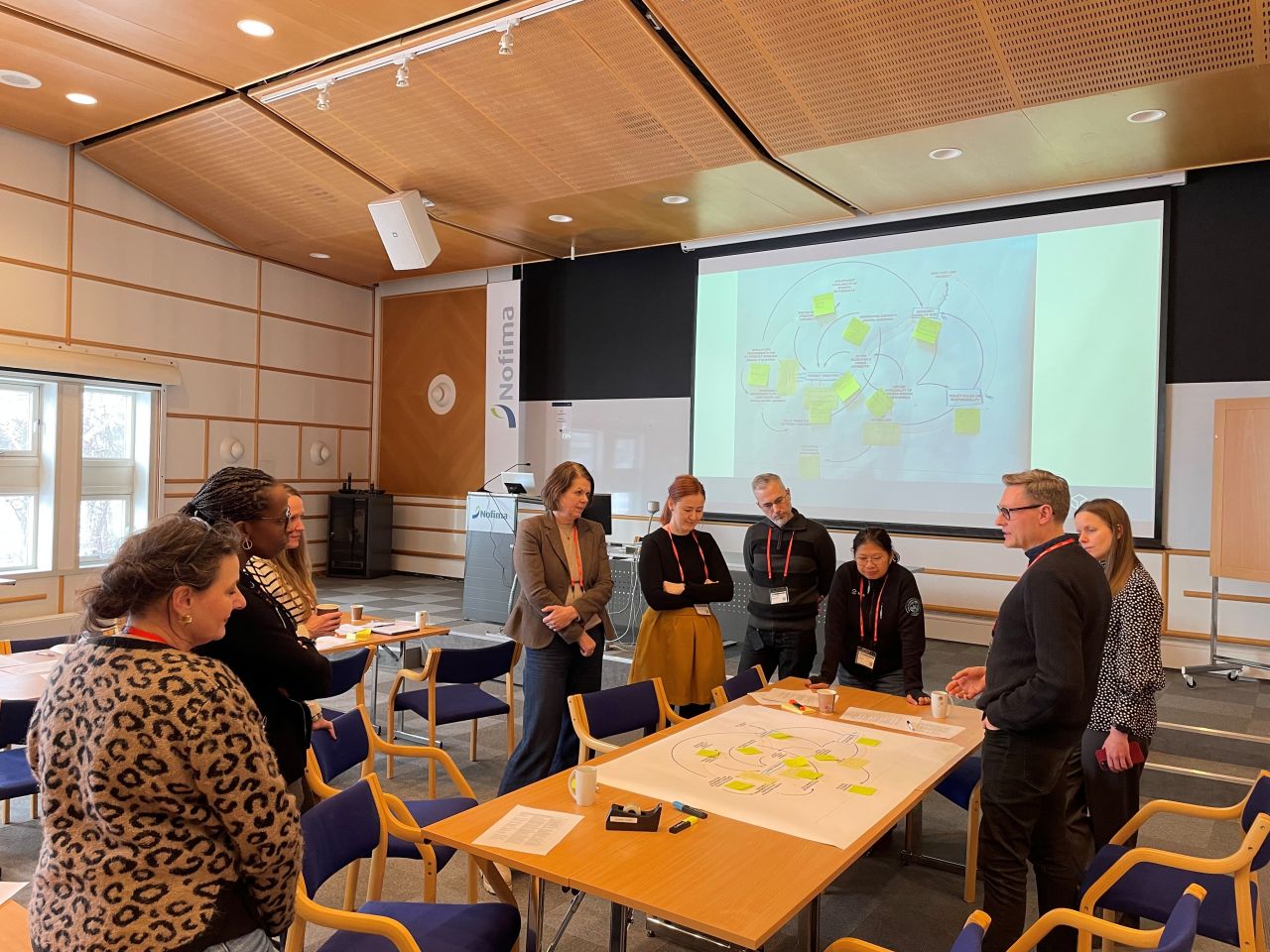 A person wearing a virtual reality headset stands in front of multiple screens, engaged in a digital experience.