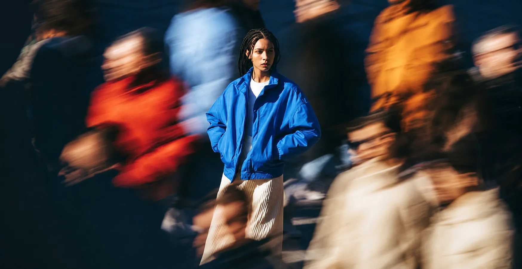 A woman stands still amid a blurred, moving crowd