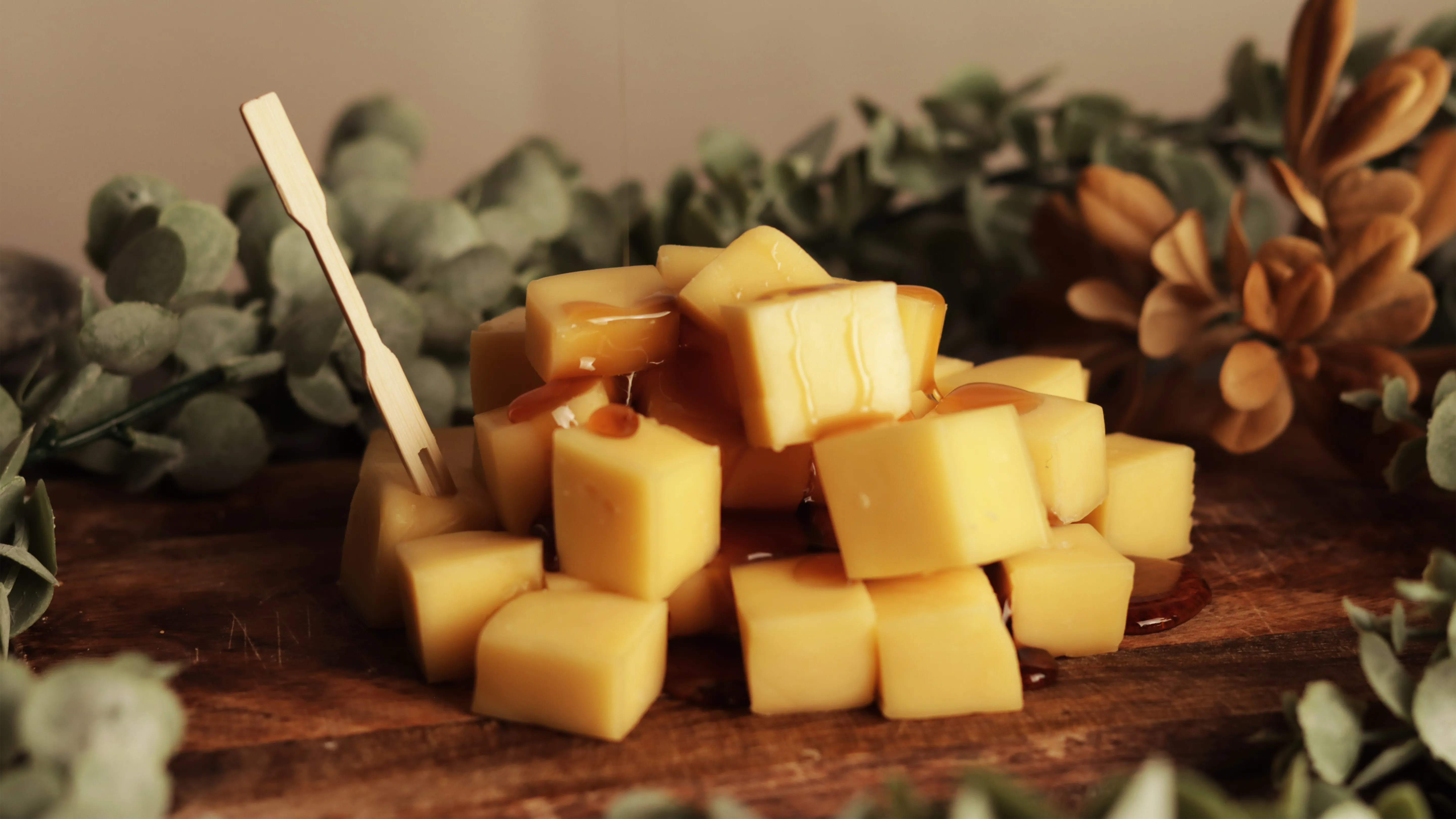 Cubos de queso con miel sobre tabla de madera