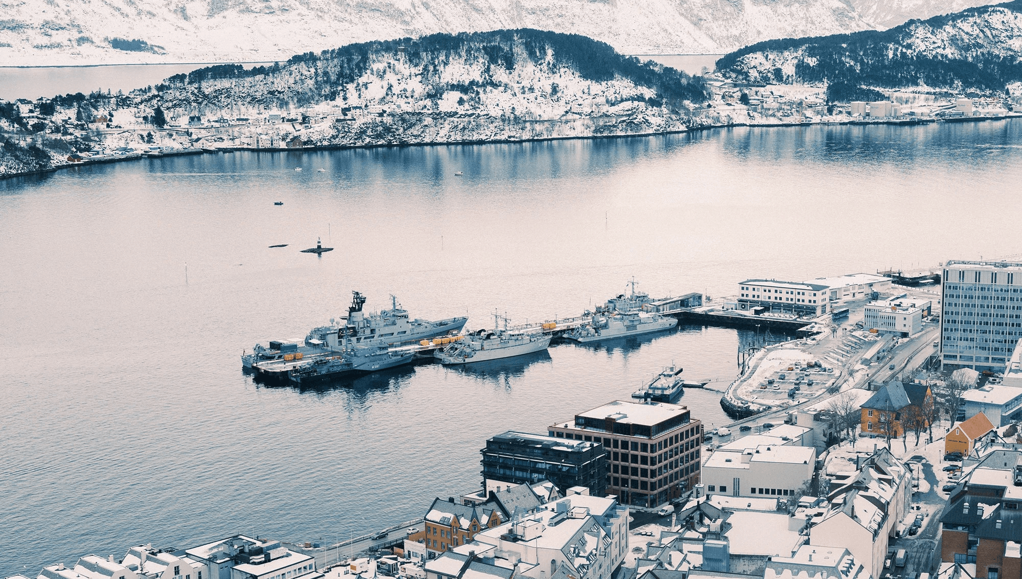 A serene icy landscape featuring floating icebergs in a calm blue water body, surrounded by snowy mountains.