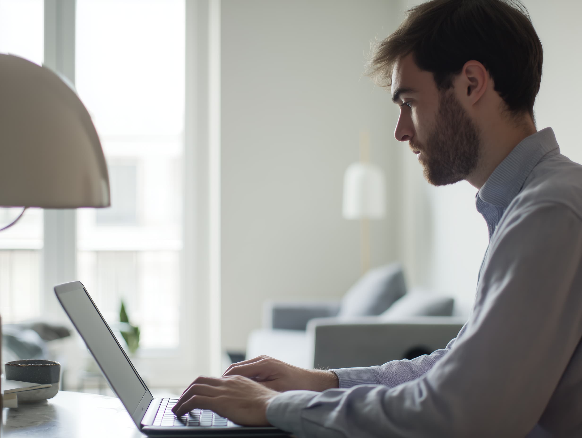 Man working on a laptop at a desk in a clean, professional home workspace