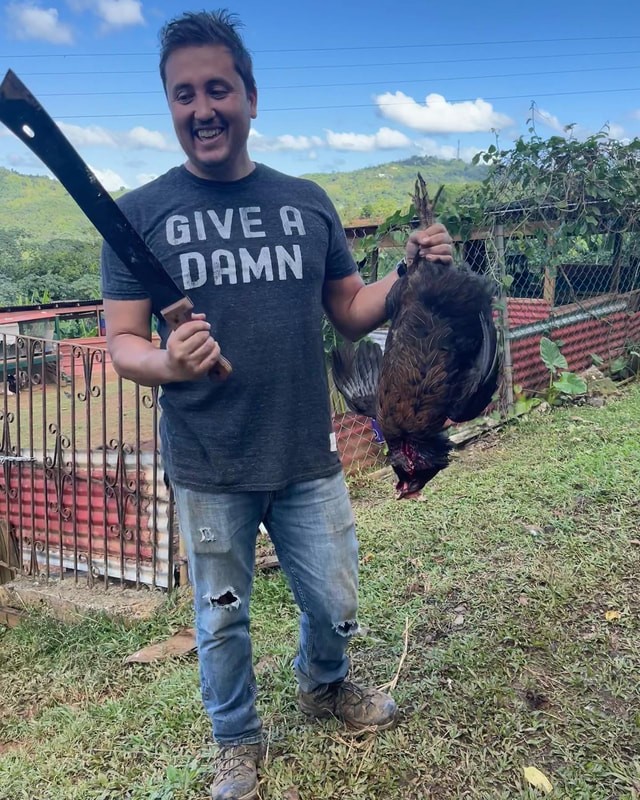 Crew member in Give a Damn t-shirt holding a chicken on location in Puerto Rico