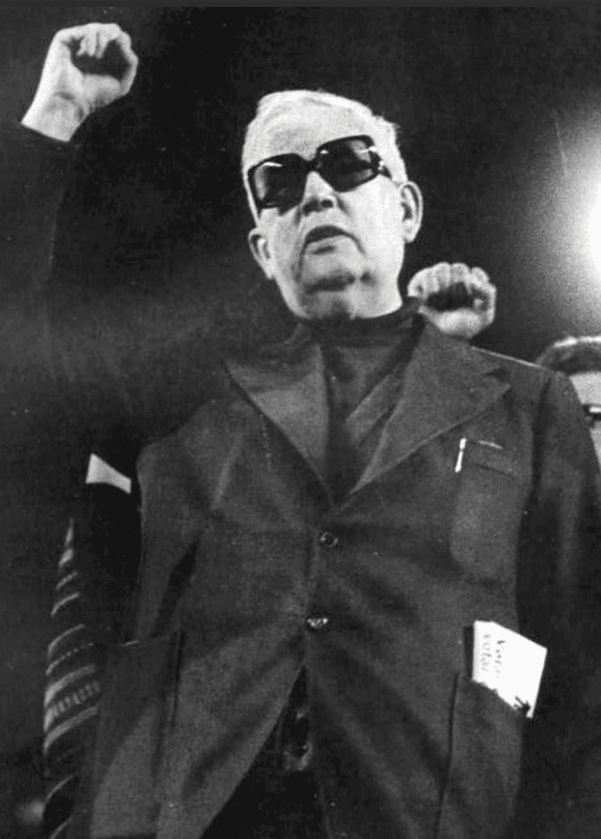 View of the French countryside through a stone villa’s open living room, with sofas and trees framing the scene