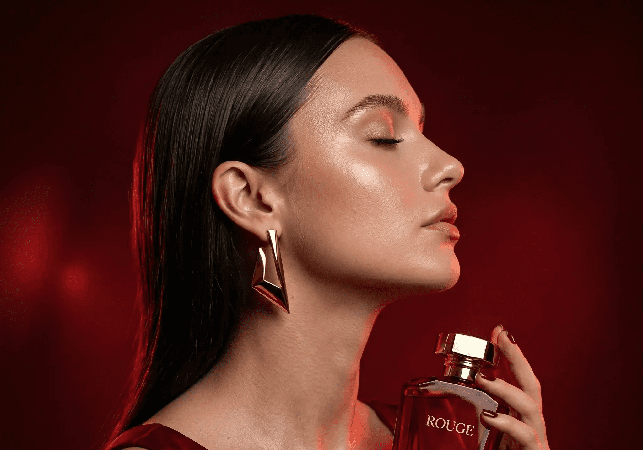 A visual marketing example showing a woman holding a bottle of Rouge Élégance Paris perfume under atmospheric red lighting. This high-end product photography is used to demonstrate luxury brand positioning by Mahindra, a specialist consultant and digital marketing trainer, who analyzes visual content strategies as a marketing trainer.