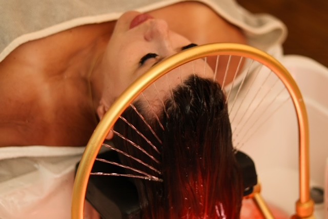 A person lying on a massage table, their face covered with a towel, bathed in warm golden light. The setting exudes relaxation and comfort.