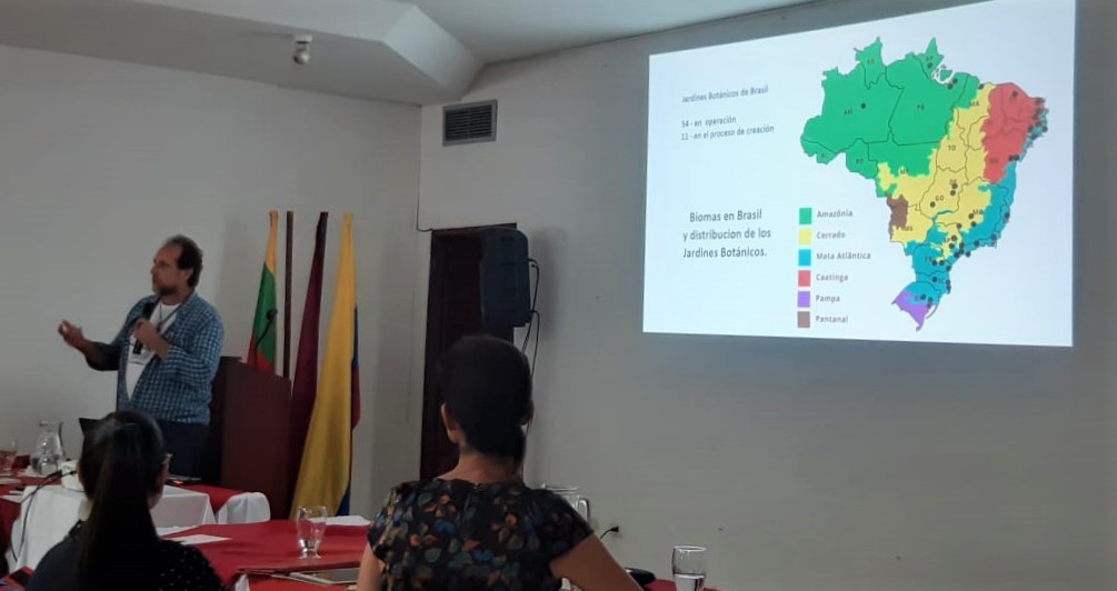 Palestrante apresenta mapa do Brasil com biomas projetado na parede durante encontro de jardins botânicos