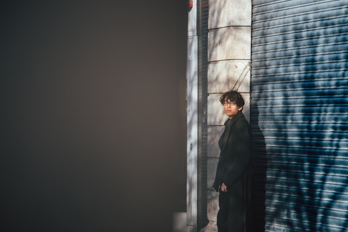 Person stands near a wall with tree shadows