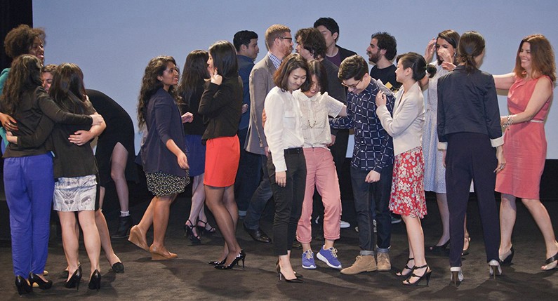 students and alumni on the stage hugging each other